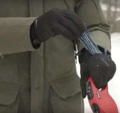 Walkease- Winter Glove Designed For people who walk dogs - Black gloves on women taking out poop bags from pocket on gloves. 