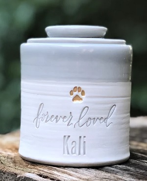 Simple white and gray urn with a name carved into the ceramic. 