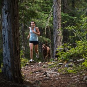Women running in wood with dog.  Location is unknow