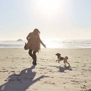 How to celebrate dog moms on Mother's Day; women on beach running with dog.