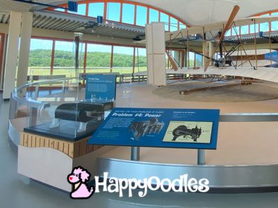 Visiting the Wright Brothers Monument in NC with a dog- Replica of Wright Plane - Happyoodles logo.